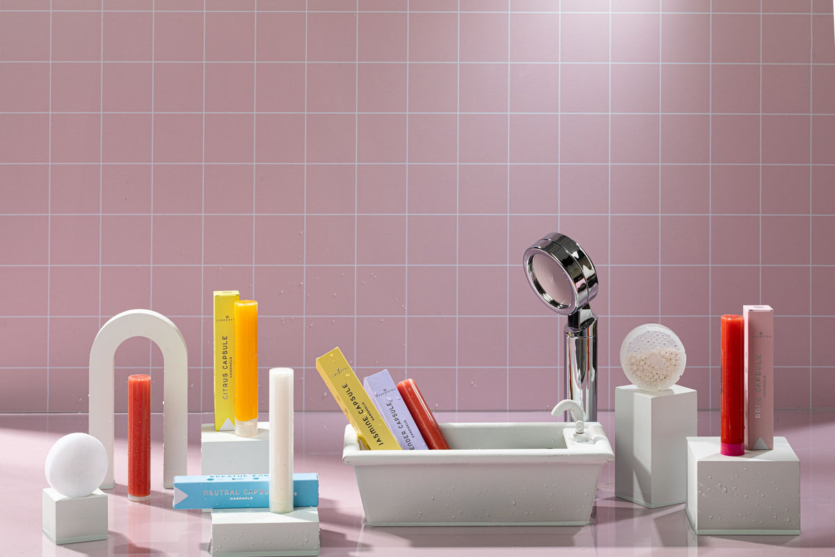 Luscentra handheld shower filter and colorful capsules in a pink bathroom display.