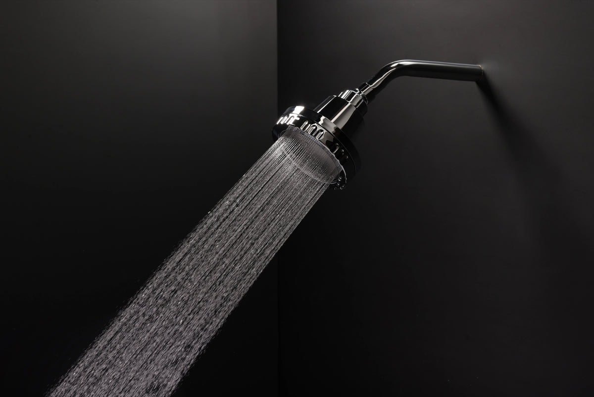 Water flowing from a chrome Luscentra showerhead against a dark shower wall.