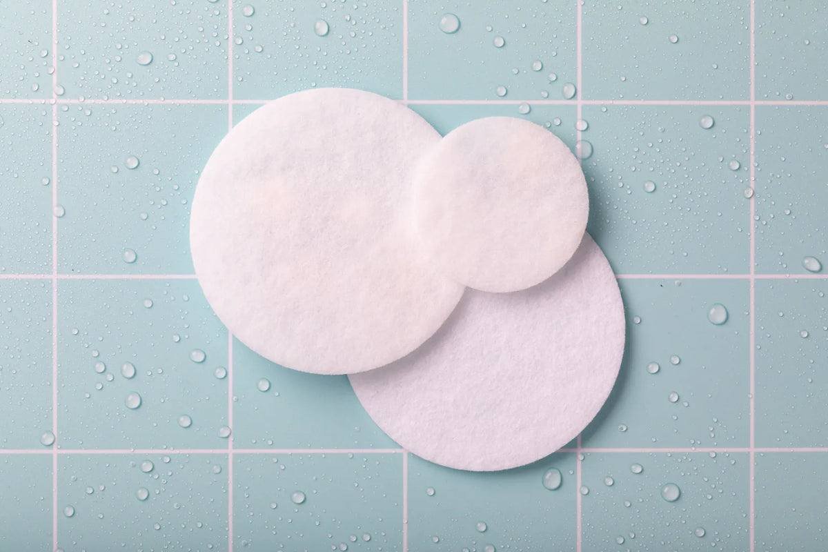 Clean and used round microfibre shower-filter cloths on blue tile.