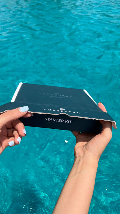Hands holding a black Luscentra starter-kit box over a swimming pool.