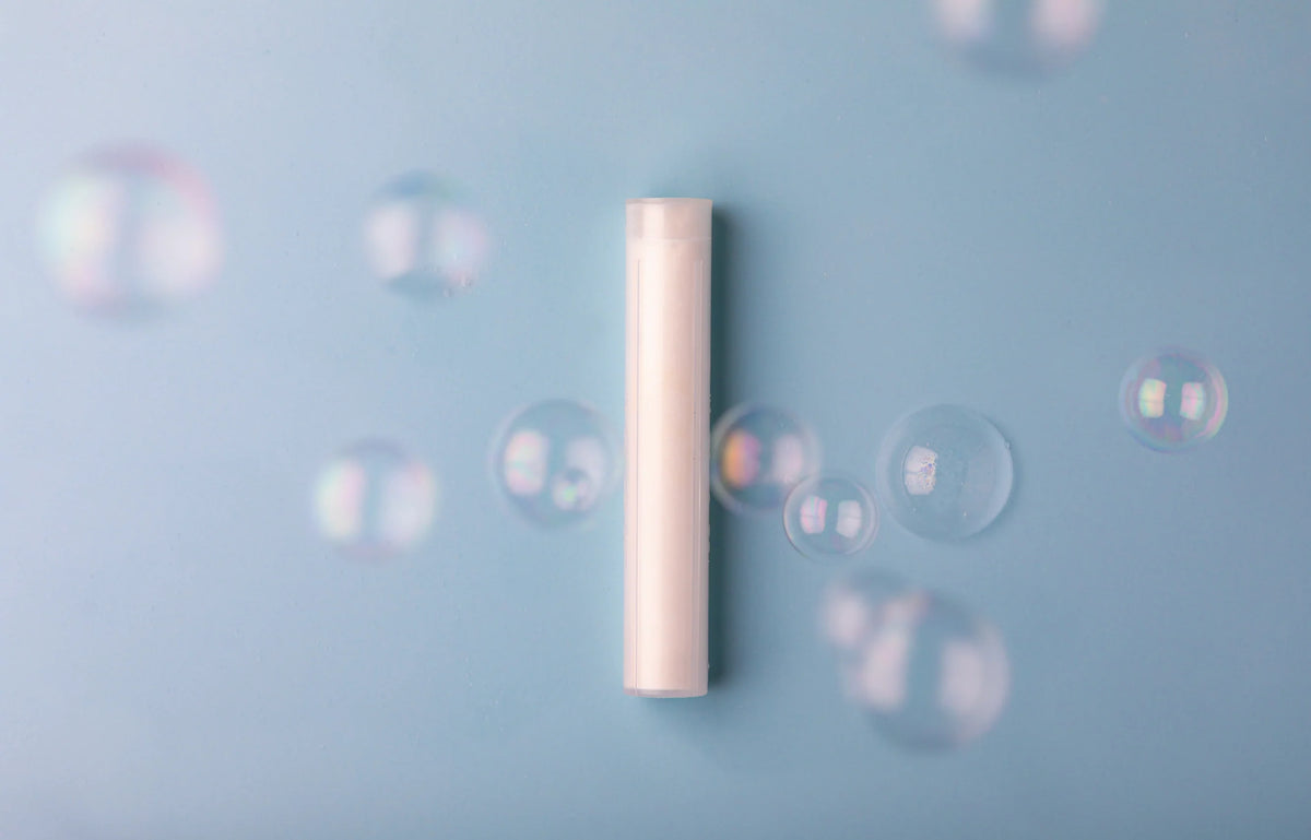 Neutral Luscentra vitamin C shower capsule surrounded by bubbles.